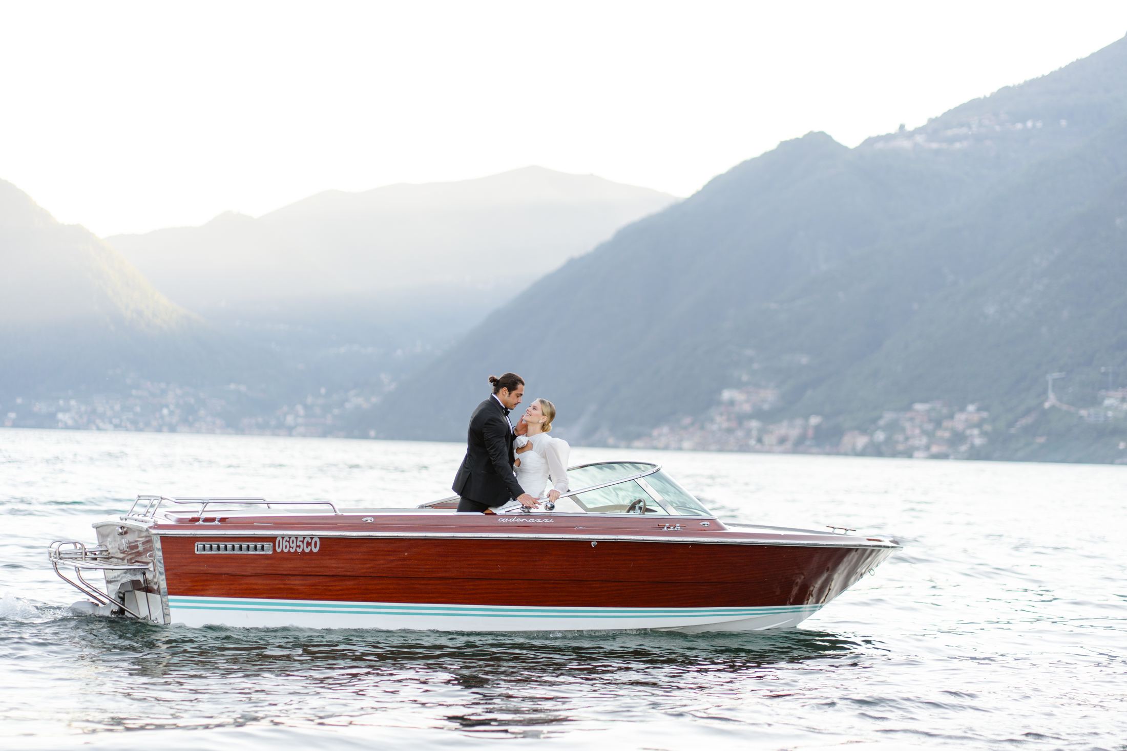 Bride and groom crossing a lake in a classic wooden boat