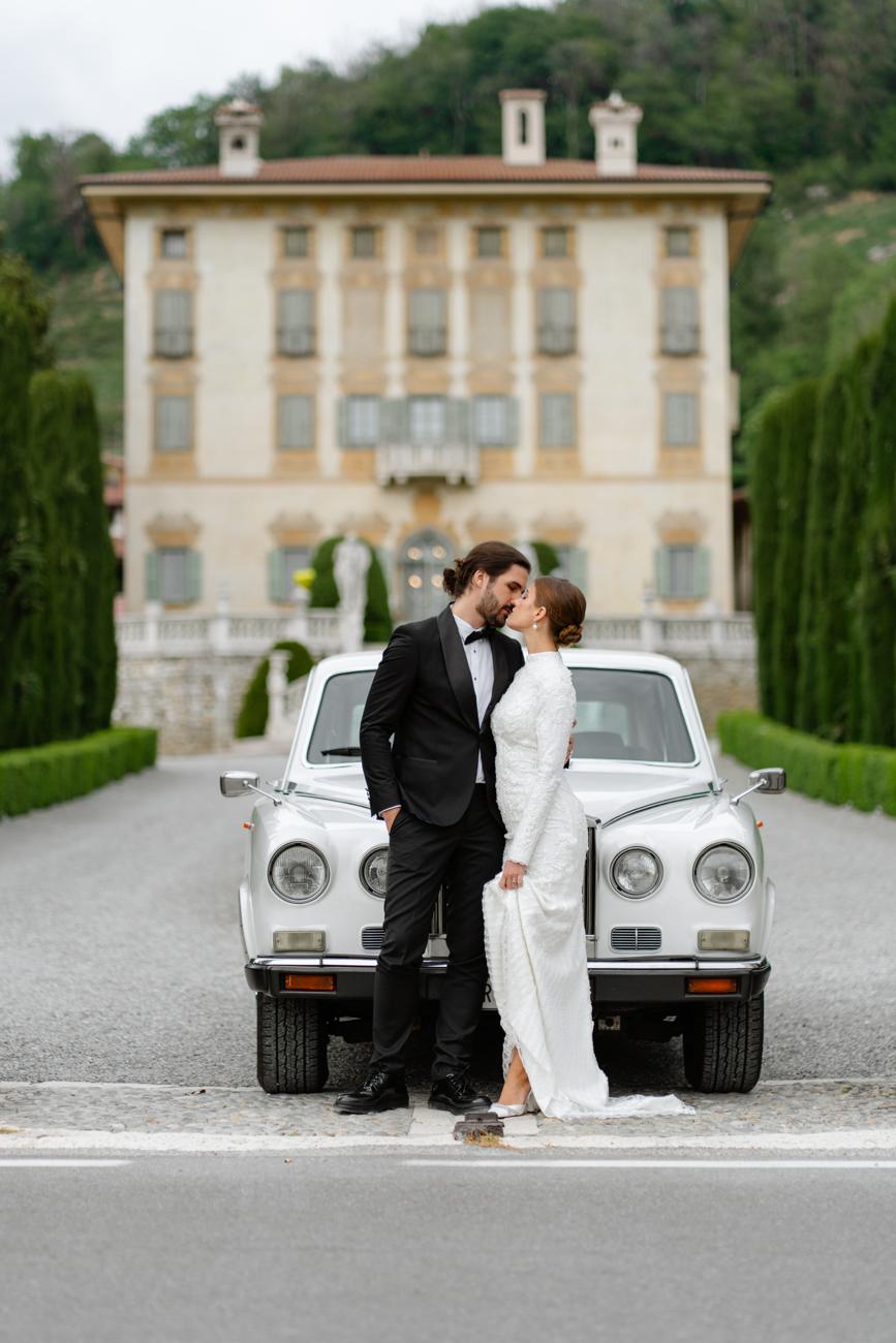 Couple with a white classic car before the villa
